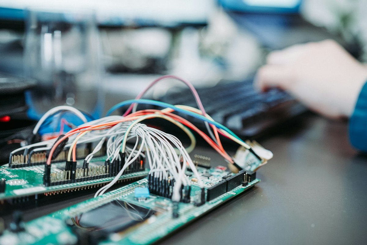 Hands wiring an electronics prototype on a workbench